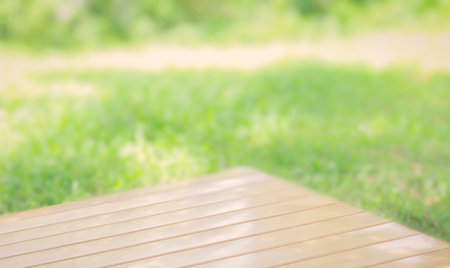 wooden desk outdoor on green lawn,smooth planks the bright sunlight. Natural texture light, blurred background of grass, peaceful backyard scene.の写真素材