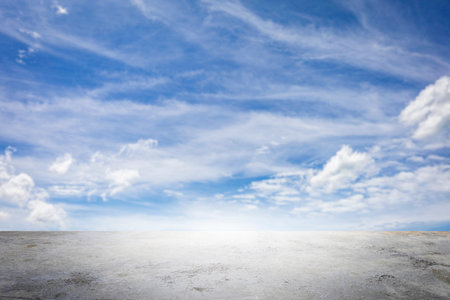 Wide empty grunge cement counter table top on blue sky clouds white light background for business product windy scene, blue sky empty land back a concrete road cutting through, as clouds drift in the windy background, creating a serene landscape by the park.の写真素材