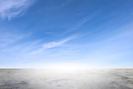 Wide empty grunge cement counter table top on blue sky clouds white light background for business product windy scene, blue sky empty land back a concrete road cutting through, as clouds drift wayの写真素材