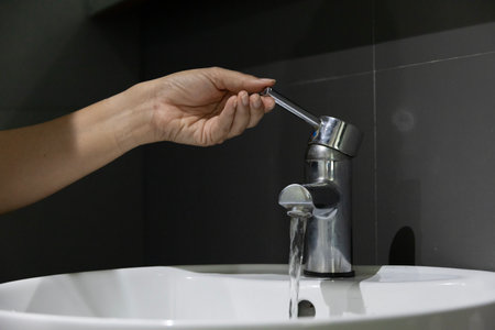 close up Woman open pull chrome faucet washbasin to washing hand soap for at water tap. push off water running drop off. Bathroom interior background with sink basin faucet tap.の写真素材