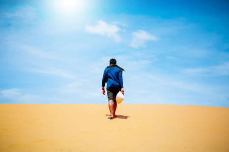 man walking through desert sand dunesの写真素材
