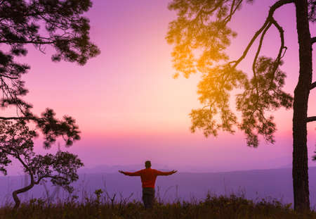 Silhouette of young man on sunset or sunrise in pine forest. Confident teenage boy thinking.Freedomの写真素材