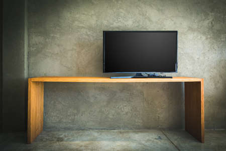 Flat LCD television on wood table in the living room with grunge concrete wall and parquet floorの写真素材