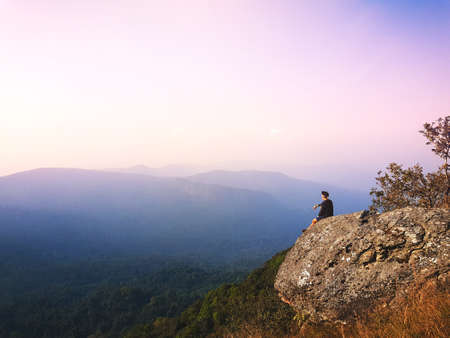 young man  Asia tourist  at mountain is watching over the misty and foggy morning valley to sunrise, travel.Trekkingの写真素材