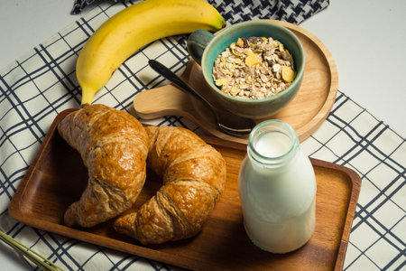 Breakfast served with croissants,milk,cereal and bananaの写真素材