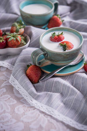 Fresh strawberries and cup of milk on a tablecloth. Strawberries in milkの写真素材