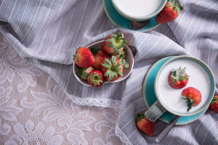 Fresh strawberries and cup of milk on a tablecloth. Strawberries in milkの写真素材