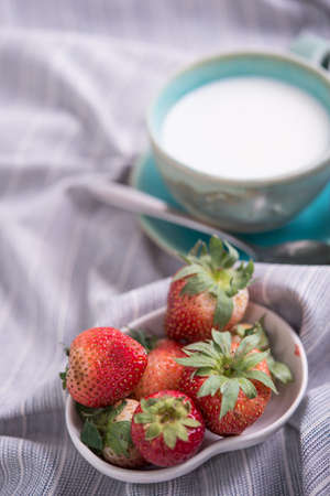 Fresh strawberries and cup of milk on a tablecloth. Strawberries in milkの写真素材