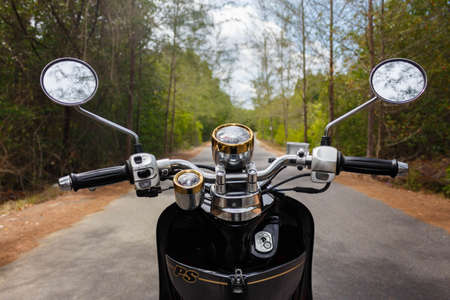 motorbike on an empty road in a sunny forestの写真素材