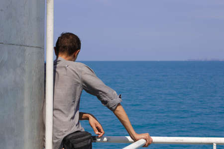 lonely guy aboard the ferry stands and looks into the distanceの写真素材