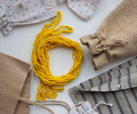 Reusable and paper bags for shopping in the store on a light wooden background. Zero waste concepの写真素材