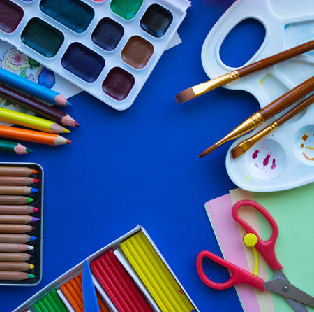Hobby. Watercolor paints, palette, brushes, pastel, color pencils, plasticine on a blue background...