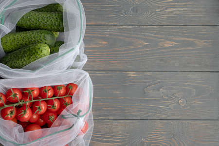 Fresh vegetables and fruits in a reusable eco-friendly pouch on a wooden background with space for your text.の写真素材