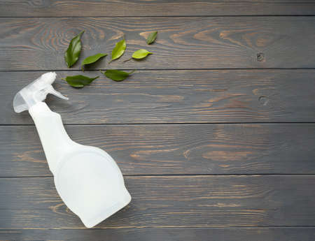 Plastic bottle with liquid for cleaning glass, plumbing, tiles or floor and green herbal leaves on a gray wooden background with space for text. Natural organic cleaning product. Eco-concept. Poster.の写真素材