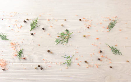 Background with dill leaves, pink salt and pepper on a white wooden background with space for text....
