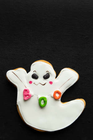 Gingerbread gingerbread in the shape of a ghost for halloween on a dark background with space for text.の写真素材