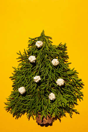 New Year concept - alternative tree made of cypress branches on a yellow background with space for text. Postcard template, poster.の写真素材