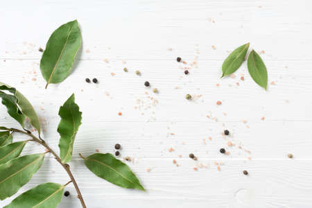 Bay leaf and peppercorns on a white wooden background with space for text.の写真素材