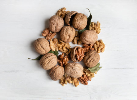 Walnut whole and peeled on a white wooden background.