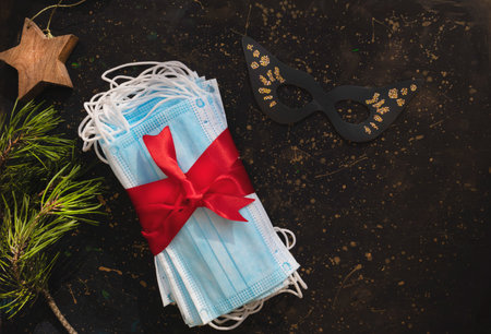 Hygienic face masks as a gift with a red ribbon framed with fir branches. Christmas and New Year...