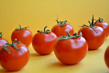 Red cherry tomatoes on a yellow 2D background. Healthy food concept. Banner.の写真素材