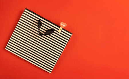 Gift bag with a heart on a red background with space for text.の写真素材