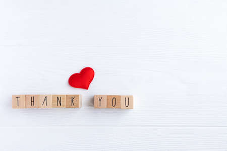 The word thank you on wooden cubes and a red heart on a light background with space for your text.の写真素材