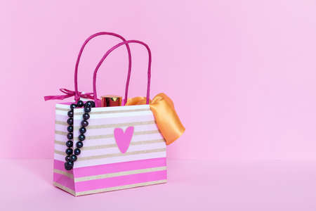A paper bag with gifts or purchases on a pink background. The concept of a gift.の写真素材
