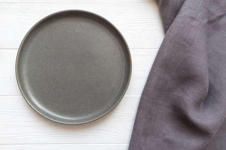 Grey ceramic plate on wooden background with linen towel and space for your text. Template.の写真素材