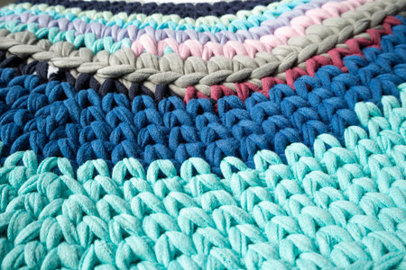 The mat is made of knitted yarn, hand-knitted on knitting needles. Home needlework.