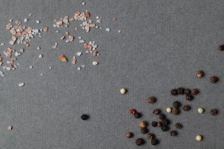 Crystals of pink salt and spices from black, white and pink pepper on a dark background with space...