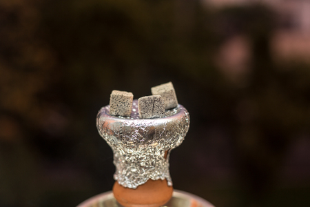 Preparing the shisha, aka nargile or hookah at a restaurant by placing the charcoals on top. A very middle eastern custom.の写真素材
