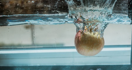 An Apple dip in aquarium with water splashesの写真素材