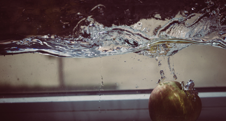 An Apple dip in aquarium with water splashesの写真素材
