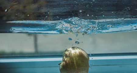 An Apple dip in aquarium with water splashesの写真素材