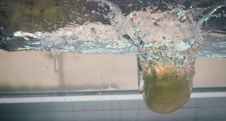 An Apple dip in aquarium with water splashesの写真素材