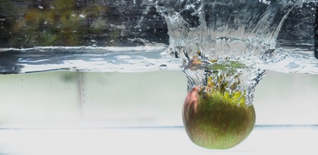 An Apple dip in aquarium with water splashesの写真素材