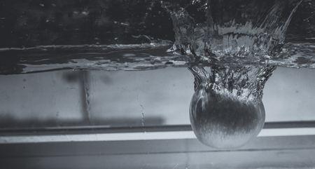 An Apple dip in aquarium with water splashesの写真素材