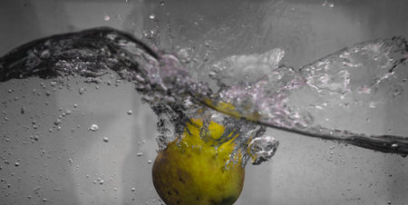 An Apple dip in aquarium with water splashesの写真素材