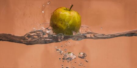 An Apple dip in aquarium with water splashesの写真素材