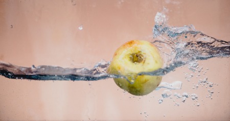 An Apple dip in aquarium with water splashesの写真素材