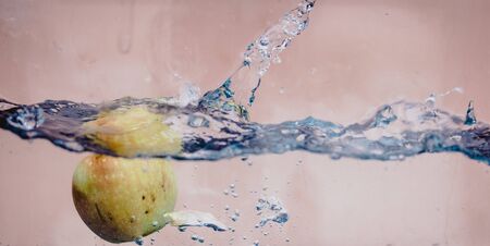 An Apple dip in aquarium with water splashesの写真素材