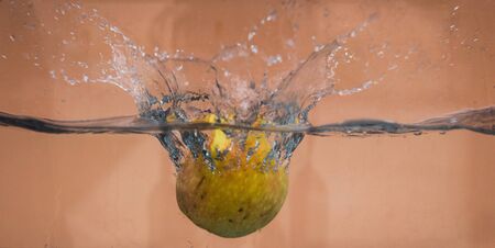An Apple dip in aquarium with water splashesの写真素材