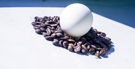 Coffee beans and Easter egg, dyed with coffee on a background of burlapの写真素材
