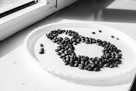Coffee beans in form of number 8 and orchids on white plastic plate. International women's day. 8th marchの写真素材