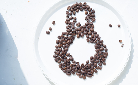 Coffee beans in form of number 8 and orchids on white plastic plate. International women's day. 8th marchの写真素材