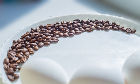 Coffee beans in moon shape on white plateの写真素材