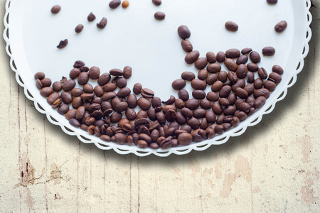Coffee beans on a white plastic plate. On beautifull wooden background. Love. Insparation. On white plate. Romantic.の写真素材
