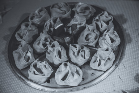Preparation of manti on a kitchen wooden board. Traditional asian dumplings. Mantu are filled with beef or lamb mixed with minced onions and spices.の写真素材