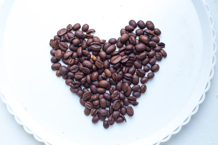 Coffee beans in form of heart on beautifull background. Love. Insparation. Romantic. On white plate.の写真素材